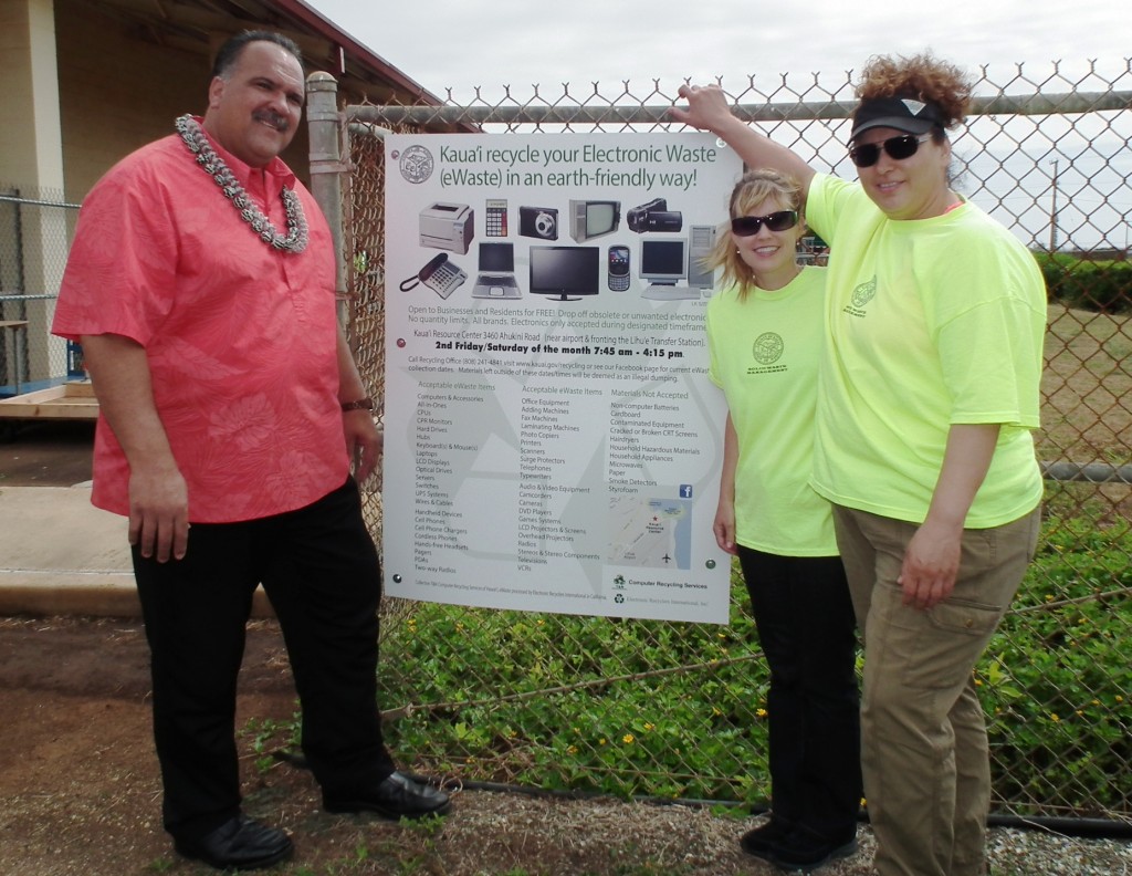 Mayor Bernard Carvalho, Jr. and two members of the county recycling team – Allison Fraley, Solid Waste program development coordinator, and Laura Kelly, recycling specialist – stand beside a sign announcing the county’s new eWaste Recycling Program at the Kaua'i Resource Center.