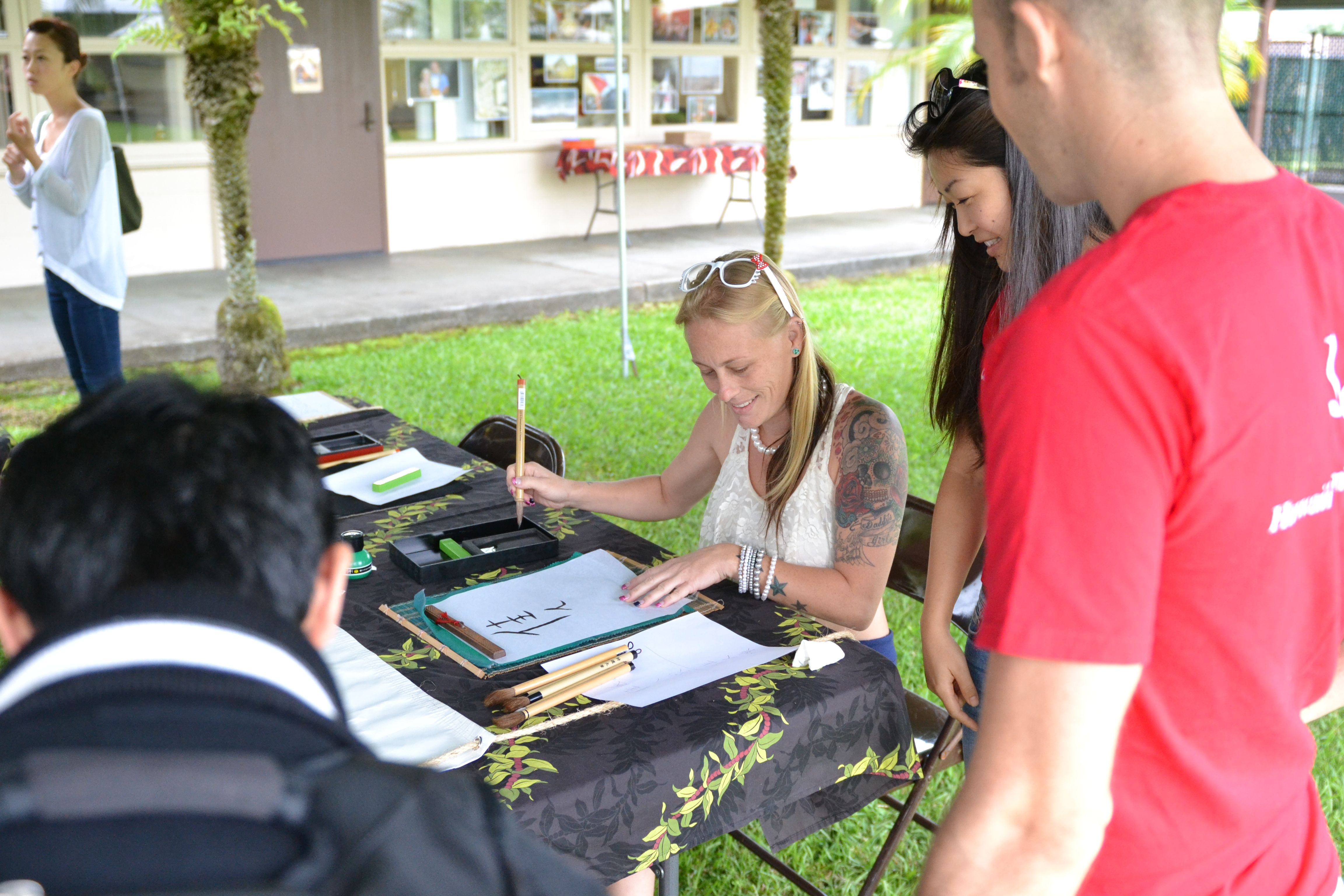 Hawai'i Community College Liberal Arts student Caitlyn Christensen, center, learns calligraphy during an International Education Week workshop.