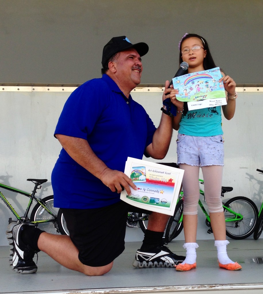 Zixin He, a fourth grade student at Kapa‘a Elementary School and grand prize winner of the county’s “I Love My Community” art contest, describes her artwork to Mayor Bernard Carvalho Jr. and the crowd at the Seventh annual Mayor-a-thon.
